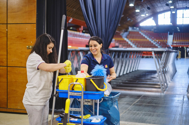 Zwei Mitarbeiterinnen stehen lachend an einem Reinigungswagen